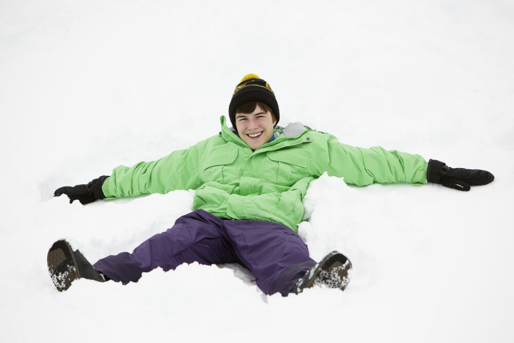 Teenage Boy Making Snow Angel On Slope
