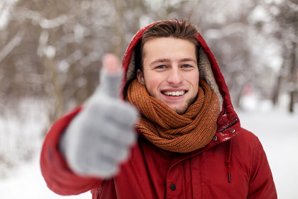 happy man in winter jacket showing thumbs up